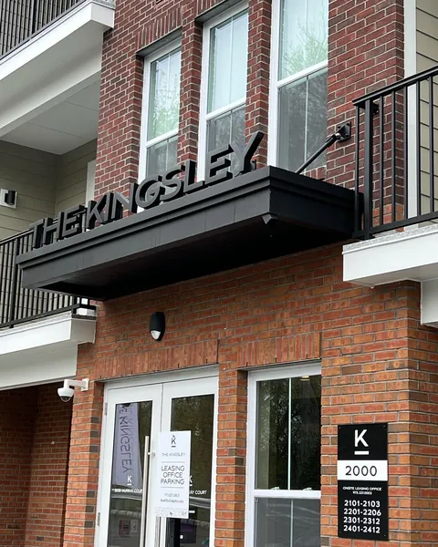 Black aluminum entrance canopy above glass doors on a red brick building.