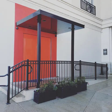 Black aluminum canopy with recessed lighting above orange double doors.