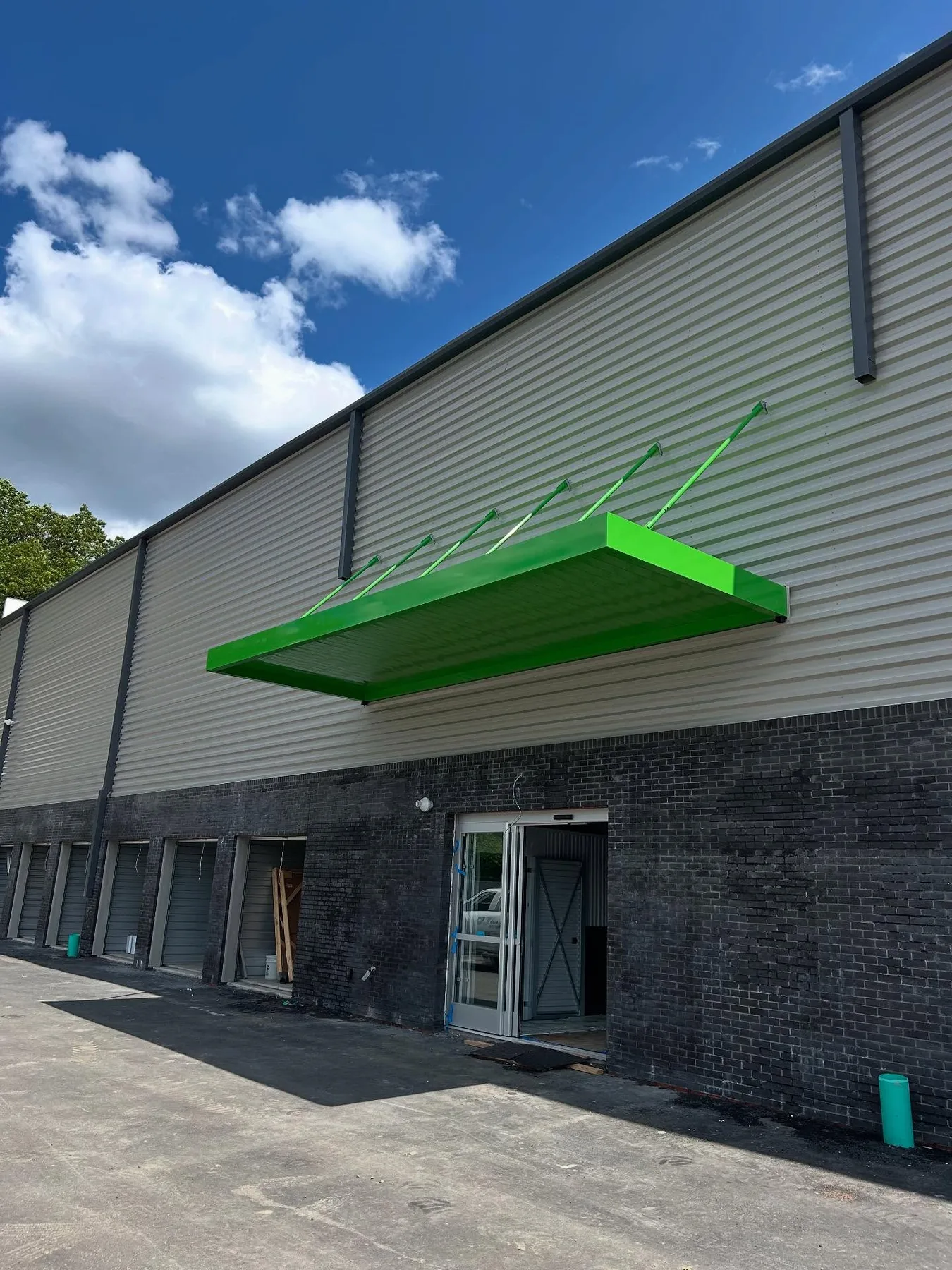 Green aluminum entry canopy on a commercial building exterior.