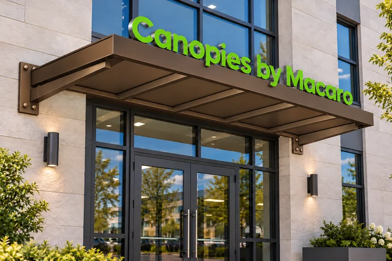 Custom black aluminum entrance canopy with green Canopies by Macaro lettering.