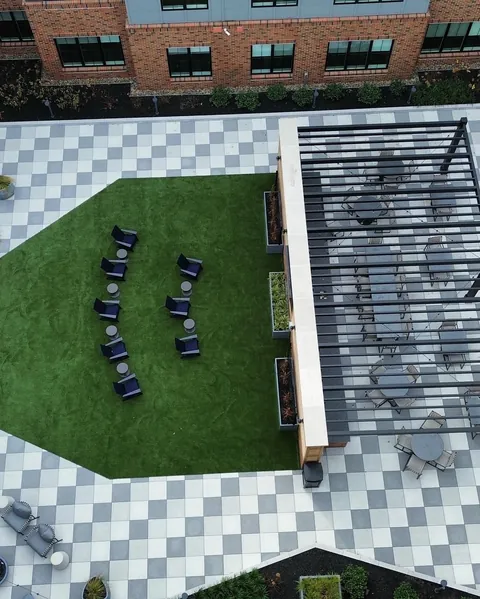 Overhead view of a black louvered pergola over an outdoor dining area with pavers and turf.