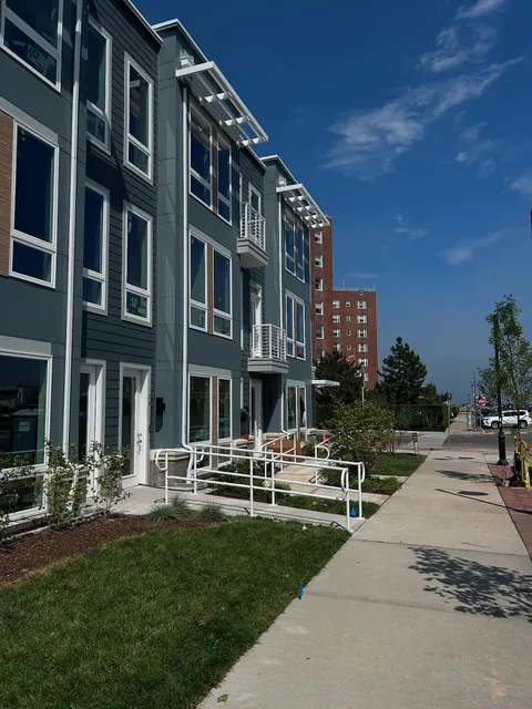 White pergola-style shade structures above top-floor windows on a multistory building.